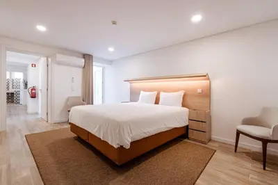 a bedroom with a large bed and a chair at Downtown Grand Houses in Porto