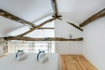 a bedroom with a white bed and wooden floors at GuestReady - Comendador Sto Ildefonso in Porto