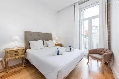 a bedroom with a bed and a chair and a window at GuestReady - Comendador Sto Ildefonso in Porto