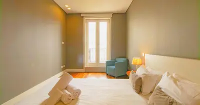 a bedroom with a bed and a blue chair at ALIADOS by YoursPorto in Porto