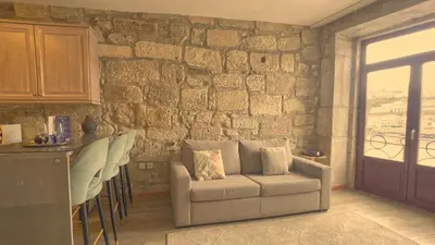 a living room with a couch and a stone wall at RIBEIRA by YoursPorto in Porto