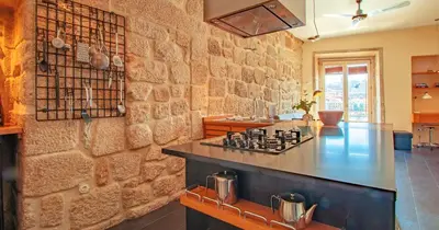 a kitchen with a counter and a stone wall at RIBEIRA by YoursPorto in Porto