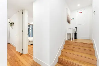 a hallway with white walls and a staircase with wood floors at Porto Calm Terrace Apartment in Porto