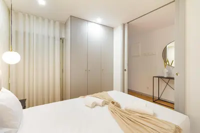 a bedroom with a white bed and a mirror at GuestReady - Cozy Vitoria Apartment in Porto