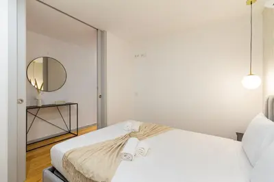 a white bedroom with a bed and a mirror at GuestReady - Cozy Vitoria Apartment in Porto