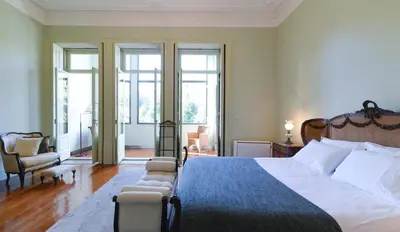 a bedroom with a large bed and chairs and windows at Maison des Amis Porto in Porto