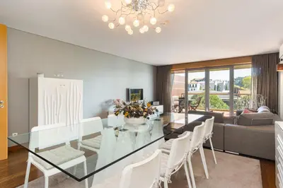 a dining room with a glass table and white chairs at GuestReady - Freixo lux with Douro River view in Porto