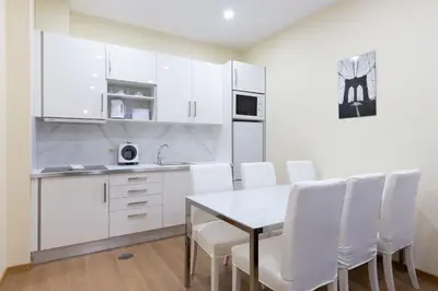 a kitchen with white cabinets and a table and white chairs at OPO Santa Catarina in Porto
