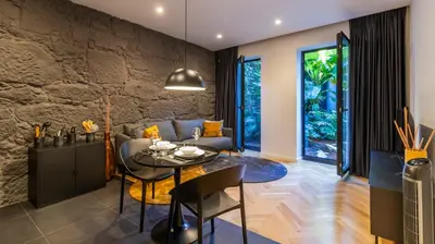 a living room with a table and a stone wall at Luxury Oasis in Bonfim by LovelyStay in Porto