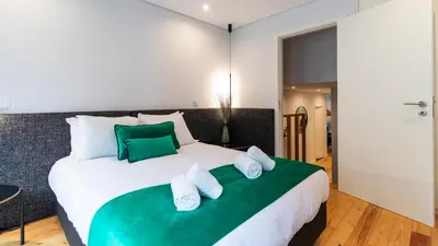 a bedroom with a large white bed with green accents at Premium 2BR Flat near Santa Catarina by LovelyStay in Porto