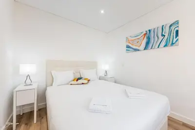 a white bedroom with a white bed and a painting at Cozy Studio-Fast Wi-Fi-Near Campanhã Station & River in Porto