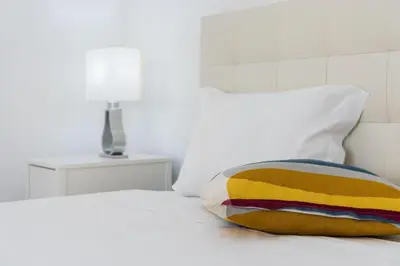 a white bed with a colorful pillow on it at Cozy Studio-Fast Wi-Fi-Near Campanhã Station & River in Porto