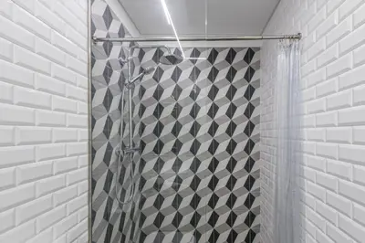 a shower with a black and white tile wall at Cozy Studio-Fast Wi-Fi-Near Campanhã Station & River in Porto
