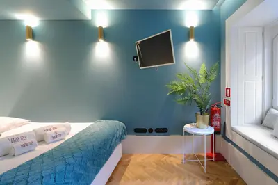 a bedroom with a bed and a tv on a blue wall at HM - Infante Riverside Apartment B in Porto