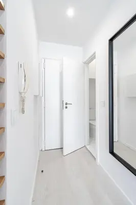 a white hallway with a mirror and a door at VIVA Marquês Studio in Porto