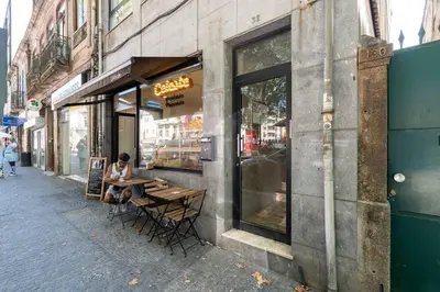 a woman sitting at a table outside of a store at VIVA Marquês Studio in Porto