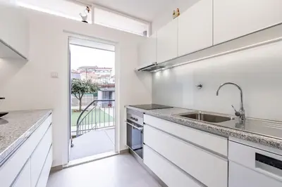 a kitchen with white cabinets and a sink at VIVA Casa do Galo in Porto