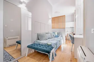 a white bedroom with a bed and a blue couch at VIVA Arts Cozy Studio in Porto