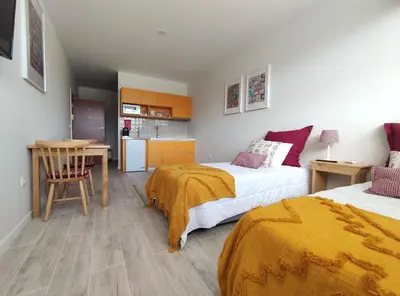 a bedroom with two beds and a table and a kitchen at Leote House - Studio 1 in Porto