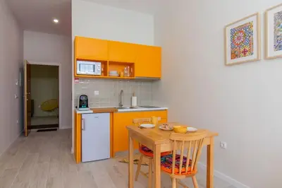 a kitchen with orange cabinets and a wooden table at Leote House - Studio 3 in Porto