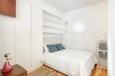 a small white bedroom with a bed and a cupboard at Boavista 2-Bedroom Apartment in Porto