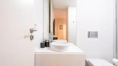 a white bathroom with a sink and two toilets at Taipas Tranquility: Cozy T0 by LovelyStay in Porto