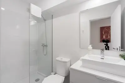 a white bathroom with a shower and a toilet and a sink at Great Location very Central Boavista in Porto