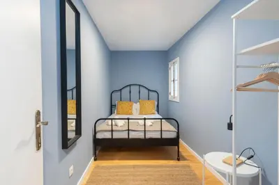a bedroom with blue walls and a bed with yellow pillows at GuestReady - Miragaia Blue in Porto