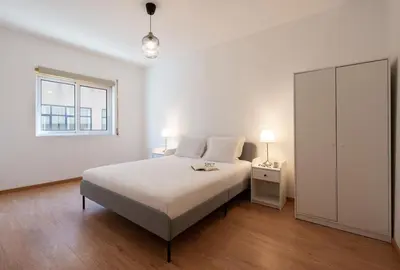 a white bedroom with a bed and a window at GuestReady - Warm and Inviting flat with balcony in Porto