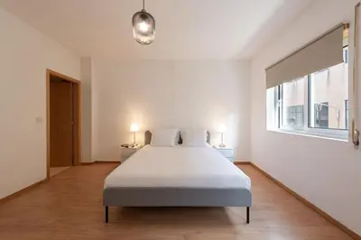 a white bedroom with a large bed and two lamps at GuestReady - Warm and Inviting flat with balcony in Porto