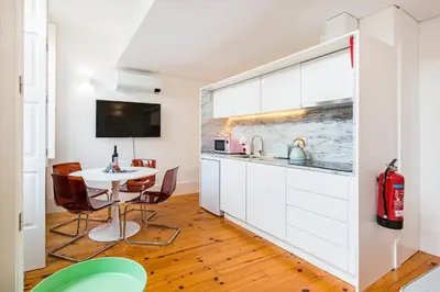 a kitchen with white cabinets and a table with chairs at GuestReady - Stylish Haven near Porto Cathedral in Porto