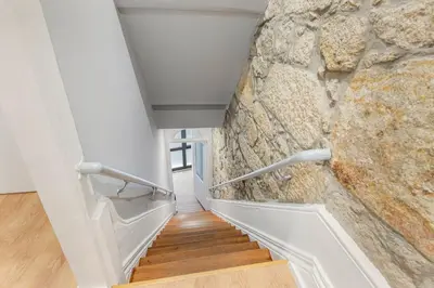 a hallway with a stone wall and wooden stairs at GuestReady - Caldeireiros Studios in Porto