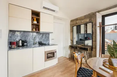 a kitchen with white cabinets and a table at GuestReady - Caldeireiros Studios in Porto