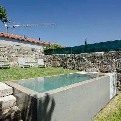 a swimming pool in a yard with a stone wall at L'Olivier 23 - 2 apartments in a recently renovated Guesthouse in Porto