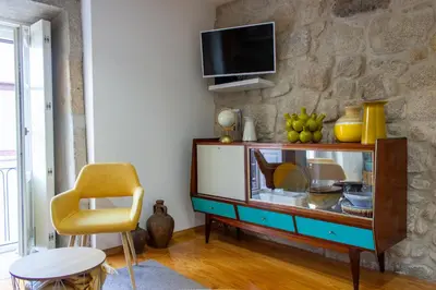 a living room with a tv on a stone wall at ORM Santana Apartment in Porto