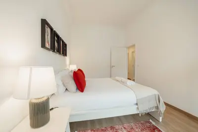 a white bedroom with a white bed with red pillows at Modern Bonfim by Hosty in Porto