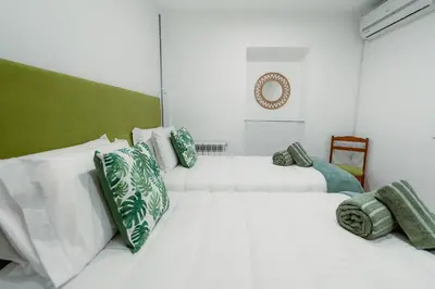 two white beds in a room with green and white pillows at Douro Garden - Authentic Portuguese Guesthouse in Vila Nova de Gaia