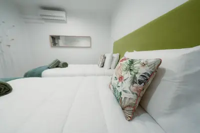 a white bed with a floral pillow on it at Douro Garden - Authentic Portuguese Guesthouse in Vila Nova de Gaia