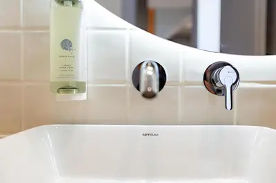 a bathroom sink with a bottle of soap next to it at Almada 505 - Premium Flat in Porto