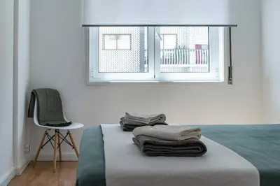 a bedroom with a bed with a chair and a window at Oliveira Monteiro Flat in Porto