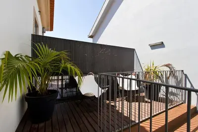 a balcony with a chair and two plants and a fence at BOUTiQUE Rentals- LOvPORTO Ribeira historic center in Porto