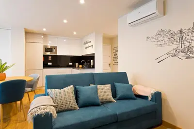 a blue couch in a living room with a kitchen at Aposentus - Sofia's House in Porto