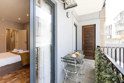 a room with a balcony with a bed and a table at Lovely Flat Marquês in Porto