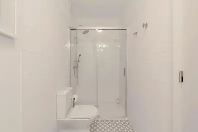 a white bathroom with a shower and a toilet at Cristelo 1 Bed next to River in Porto