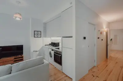 a white living room with a couch and a kitchen at Cristelo 1 Bed next to River in Porto