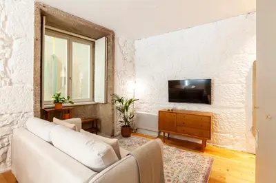 a living room with a couch and a tv on a wall at Perfect retreat in the center of Porto in Porto