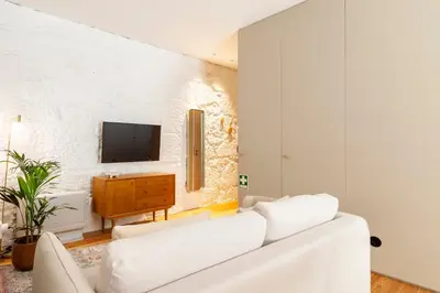 a white living room with a white couch and a tv at Perfect retreat in the center of Porto in Porto
