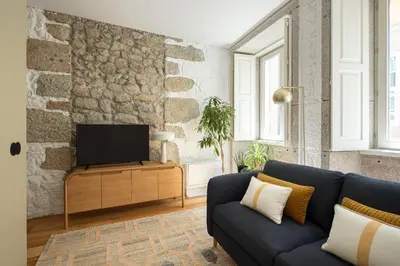 a living room with a blue couch and a tv at Elegant apartment in the historical center of Porto in Porto