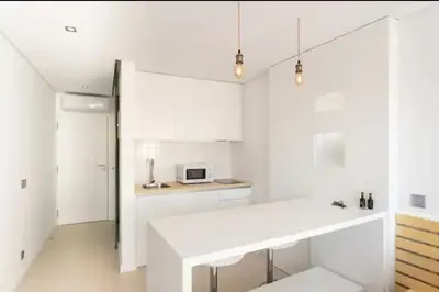 a kitchen with white cabinets and a white counter top at Cozy Studio city center in Porto