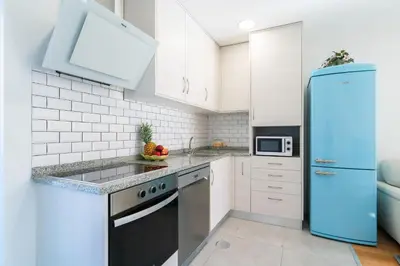 a kitchen with white cabinets and a blue refrigerator at Host Wise - Elegant Colorful House w Private Terrace in Porto